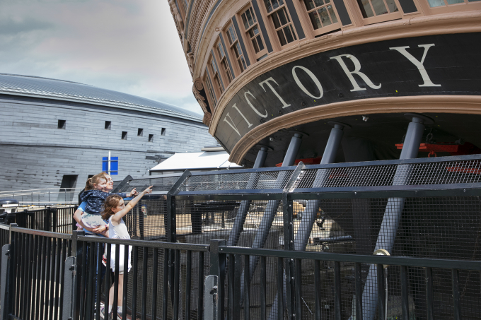 A family pointing at the stern of HMS Victory. 