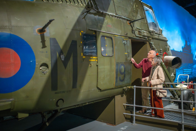 An elderly couple touching a Royal Naval Helicopter at the Fleet Air Arm Museum. 