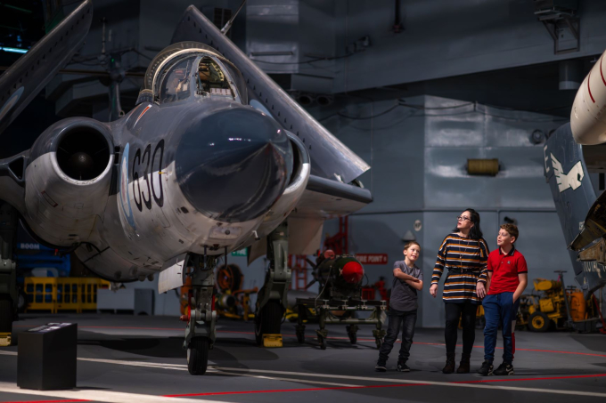 Mother and sons look up at a Royal Navy aircraft housed at the Fleet Air Arm Museum.