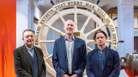 Matthew Sheldon and representatives of the University of Portsmouth stand in front of HMS Victory's wheel