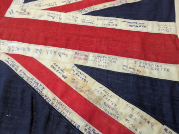 A close-up of a Union Jack flag with many names written on it.