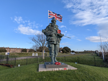 A large bronze statue of a Royal Marine with a Union Jack coming out of his backpack.