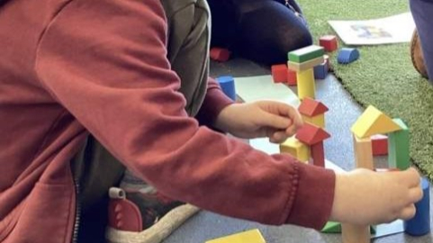A child building structures with coloured wooden blocks during 'Little Steamers: Building Bridges