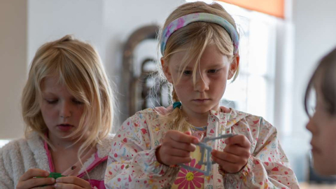 Two children concentrating on building with gears and plastic construction pieces