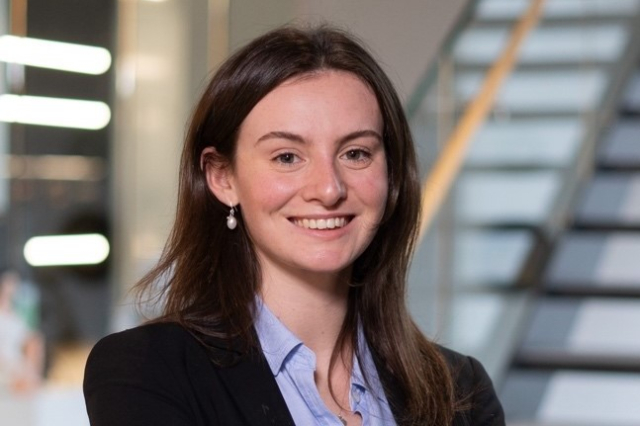 A young white woman with dark brown hair wearing a suit. 