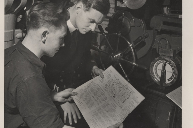 Two men read a newspaper onboard a submarine