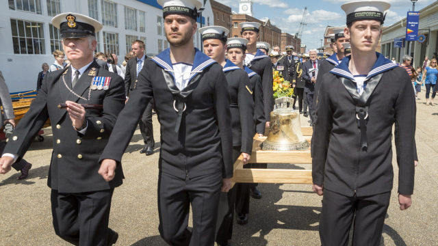 Current naval personnel carrying HMS Hood's bell through Portsmouth Historic Dockyard. 
