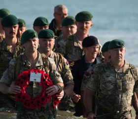 Royal Marines with a memorial walking on the beach. 