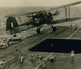 A historic image of an aircraft flying from a carrier