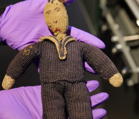 A knitted toy in the shape of sailor being held in purple gloves