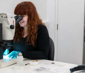 conservator looking at coins through a microscope