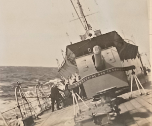 HMS Dauntless at sea rolling at an angle due to the waves. 