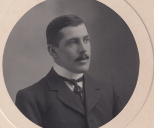 A black and white image of a man with a mousache