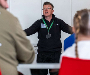 A museum educator with arms outstretched leading a session for children at the Home Educators ‘Reach an Island’ event