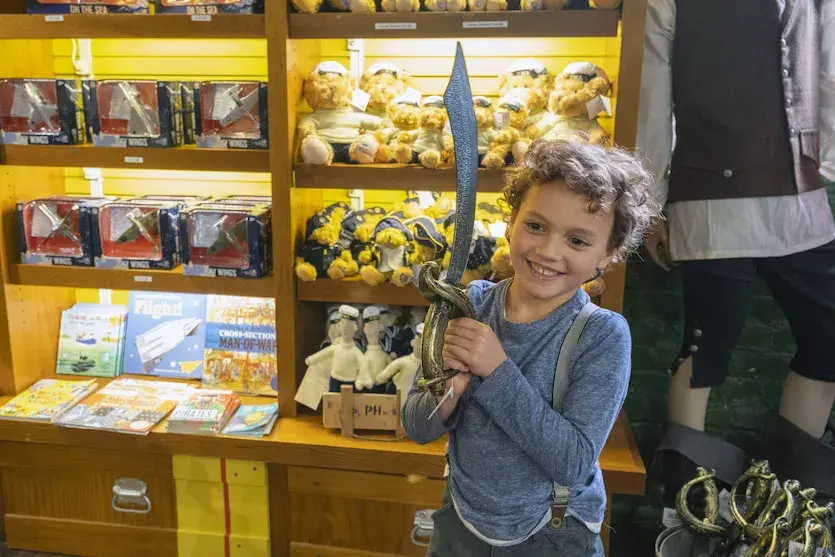 A young boy holds up a toy sword in a National Museum of the Royal Navy gift shop. 